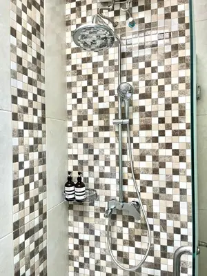 a shower in a bathroom with a checkered wall at Modern Guesthouse in Seminyak in Seminyak