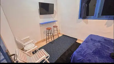 a room with chairs and a tv and a stool at A Room in Santorini House Room Near Airport Bali in Kuta