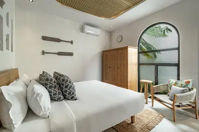 a bedroom with a white bed and a chair at Villa Tibrava Umalas by BaliSuperHost in Canggu