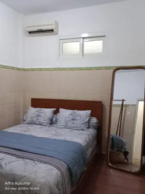 a bedroom with a bed with blue sheets and a mirror at Holiday Home Bali in Denpasar