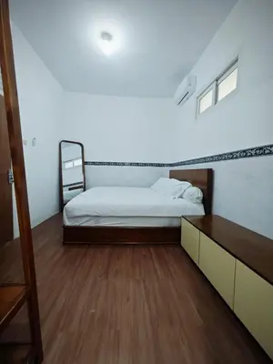 a bedroom with a white bed and a wooden floor at Holiday Home Bali in Denpasar