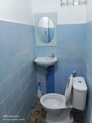 a bathroom with a toilet and a sink and a mirror at Holiday Home Bali in Denpasar
