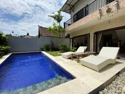 a swimming pool with two chairs and a table next to a house at Amazing Villa in Seminyak Petitenget Top Location in Seminyak