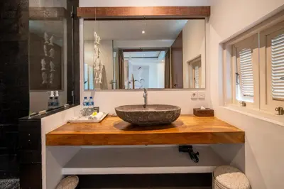 a bathroom with a stone sink and a mirror at Villa Alopa Seminyak in Seminyak