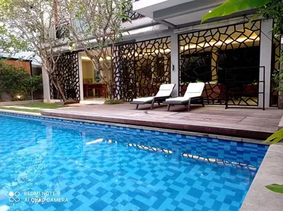 a swimming pool with two chairs next to a house at Villa Bteega sawah in Seminyak