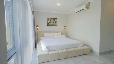 a white bedroom with a white bed with a white bedskirts at Rumah Jimbaran Kuta 3 bedroom 9 pax SukaBali 1 in Jimbaran