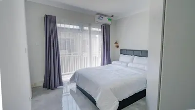 a white bedroom with a bed and a window at Rumah Jimbaran Kuta 3 bedroom 9 pax SukaBali 1 in Jimbaran