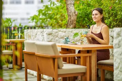 a woman sitting at a table with a glass of wine at Aahana Village Bali in Canggu