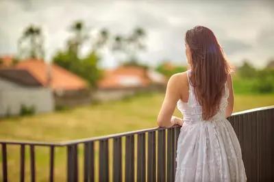 a woman in a white dress standing on a fence at Aahana Village Bali in Canggu