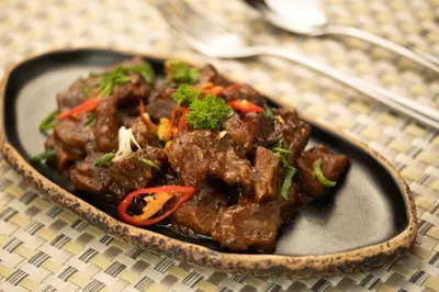 a plate of food with meat and vegetables on a table at Aahana Village Bali in Canggu
