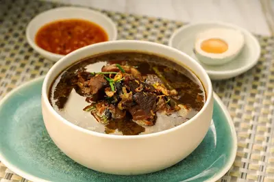 a bowl of soup on a plate on a table at Aahana Village Bali in Canggu