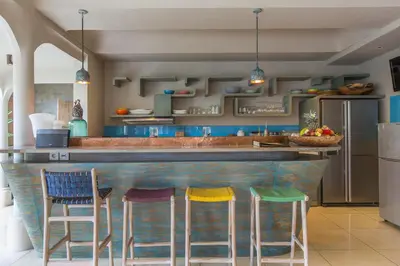 a kitchen with a bar with four stools at Villa Sky Li by Nagisa Bali in Seminyak