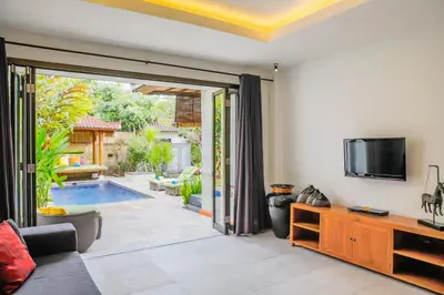 a living room with a tv and a sliding glass door at Villa Bali Caviar in Seminyak