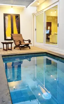 a bench sitting next to a swimming pool at Maya Kori Villa in Jimbaran