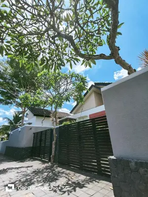 a fence in front of a house with a tree at Maya Kori Villa in Jimbaran