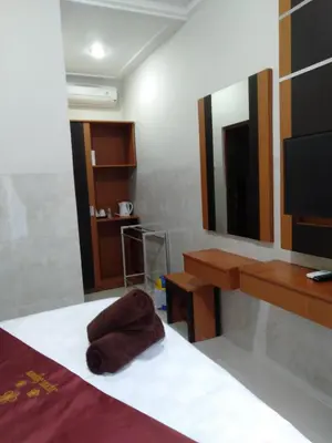 a bedroom with a bed and a mirror and a tv at Jepun Segara Guest House in Kuta