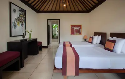 a large bedroom with two beds and a table and chairs at Villa Dewata II in Seminyak