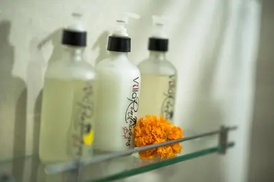 a shelf with four bottles and a flower on it at Villa Rendezvous Bali in Seminyak