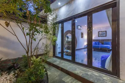 a room with large glass doors and a bedroom at Villa Blue - 4BR authentic and atypical villa in Seminyak in Seminyak