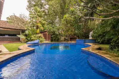 a swimming pool with blue water in a yard at Villa Blue - 4BR authentic and atypical villa in Seminyak in Seminyak