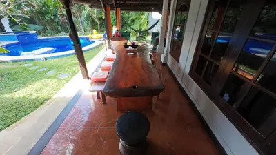 a long wooden table sitting next to a pool at Villa Blue - 4BR authentic and atypical villa in Seminyak in Seminyak