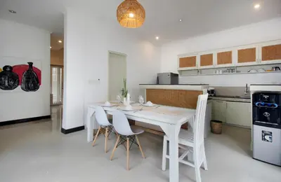 a white kitchen with a white table and chairs at Zowa Villa Seminyak byFaba in Seminyak