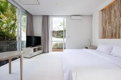 a white bedroom with a large bed and a tv at Modern 2BR Villa with Private Pool Prime Location in Seminyak