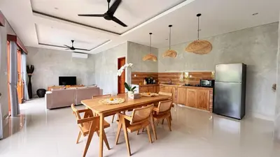 a kitchen with a wooden table and a refrigerator at Villa Bumbabu in Kerobokan