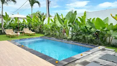 a swimming pool in a yard with chairs and plants at Villa Bumbabu in Kerobokan