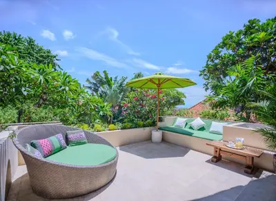 a patio with wicker chairs and an umbrella at Villa Mata Budha Seminyak in Seminyak