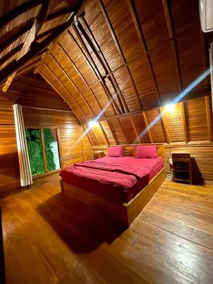 a bedroom with a bed in a wooden room at 2BR Abelle garden lumbung house in Kerobokan