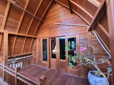a wooden cabin with a porch and a potted plant at 2BR Abelle garden lumbung house in Kerobokan