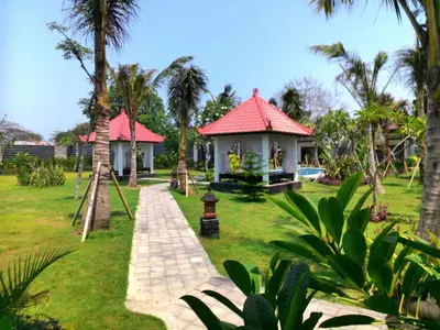 a house with a pathway leading to a yard with palm trees at D'Mell Bali in Nusa Dua