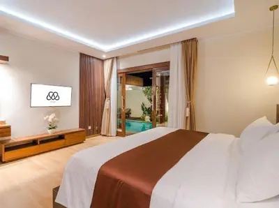 a bedroom with a large bed and a bathroom at Metta Villa in Jimbaran