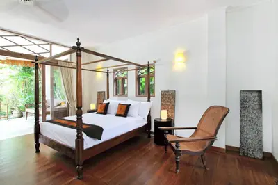 a bedroom with a canopy bed and a chair at Villa Varuna in Legian