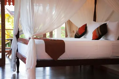 a bedroom with a bed with white sheets and pillows at Villa Varuna in Legian