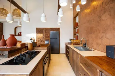 a large kitchen with wooden cabinets and a sink at Villa Galanga - Brand New Ethnic Hacienda Villa Next to Canggu with Private Pool and Parking in Kerobokan