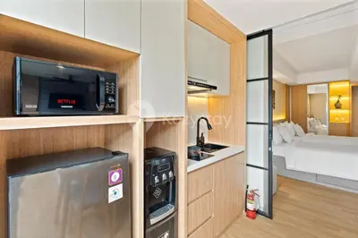 a room with a kitchen with a microwave and a bed at Palma by Kozystay - Nusa Dua in Nusa Dua