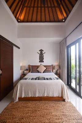 a bedroom with a bed and a large window at Sister Suites in Seminyak