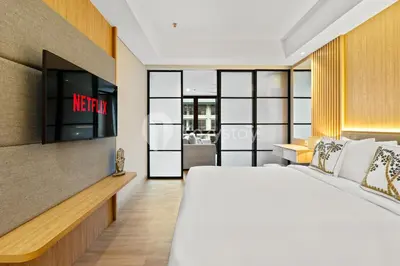 a bedroom with a bed and a tv on a wall at Olaia by Kozystay - Nusa Dua in Nusa Dua