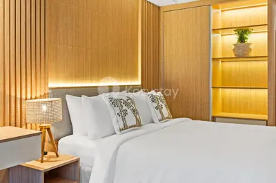 a bedroom with a white bed and a wooden wall at Olaia by Kozystay - Nusa Dua in Nusa Dua