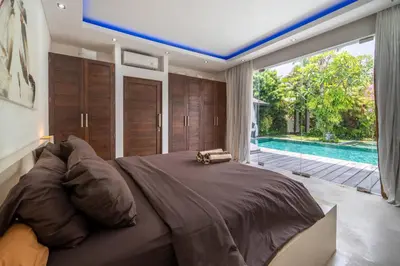 a bedroom with a large bed and a swimming pool at Villa Minha Gente Seminyak in Seminyak