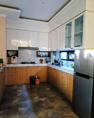 a kitchen with wooden cabinets and a stainless steel refrigerator at Room Hangtuah Sanur in Kuta