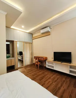 a bedroom with a bed and a flat screen tv at Room Hangtuah Sanur in Kuta