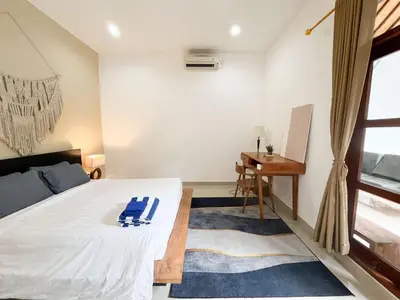 a bedroom with a bed and a desk and a window at Villa Sayang 2 in Seminyak