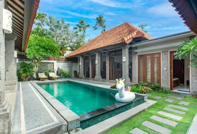 a swimming pool in front of a house with a swan at Lacita Villa Seminyak in Seminyak
