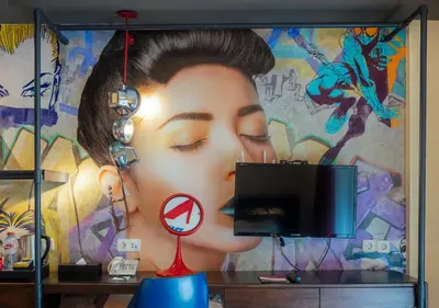 a mural of a woman on a wall with a tv at Viva Dash Hotel Seminyak in Seminyak