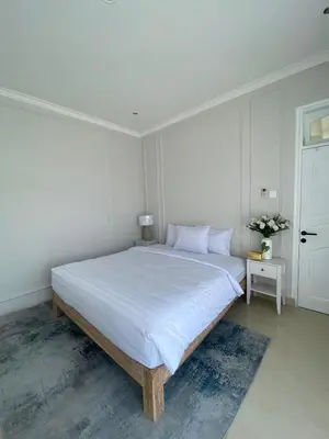 a white bedroom with a large bed with white sheets at Ara Santvana Villa Bali in Legian