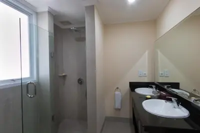 a bathroom with two sinks and a shower at Peninsula Bay Resort in Nusa Dua