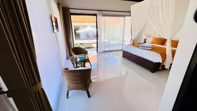 a bedroom with a bed and a table with a chair at UCU VILLAGE at ULUWATU JIMBARAN in Jimbaran